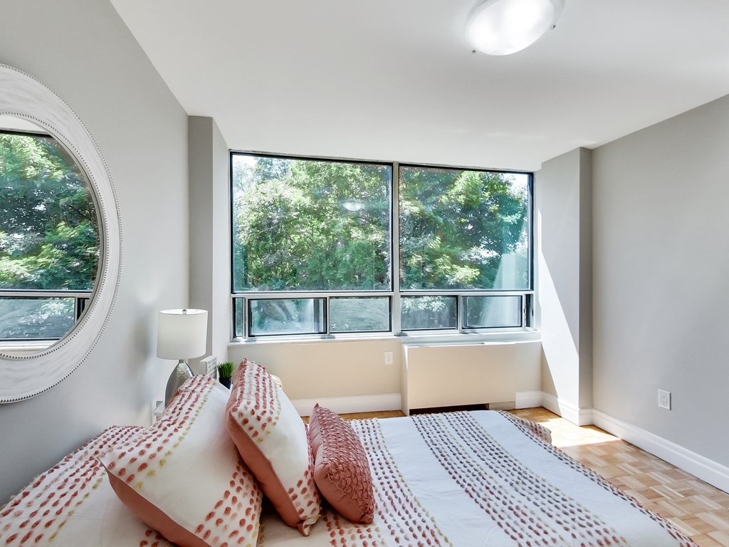 A bedroom with a large bed and a window overlooking trees.