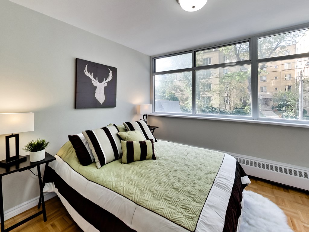 A bedroom with a bed, a deer head picture, and a window.