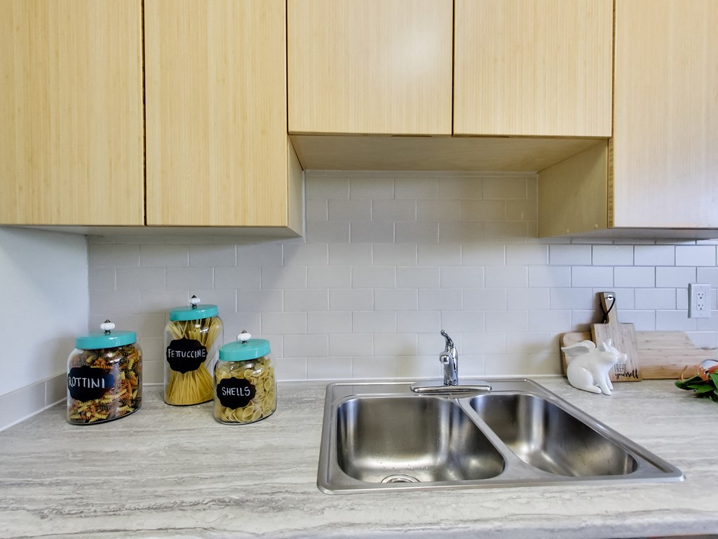 a kitchen counter with a sink and some jars on it