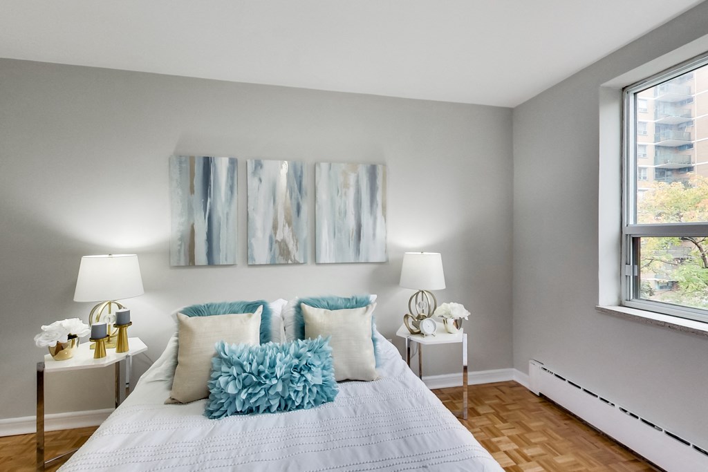 a bedroom with a bed with pillows and artwork on the wall
