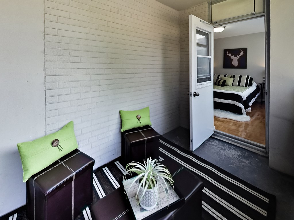 A room with a white brick wall and a bed with a black and white striped comforter.