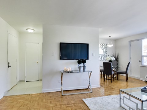 A living room with a television, chairs, and a table with candles on it.
