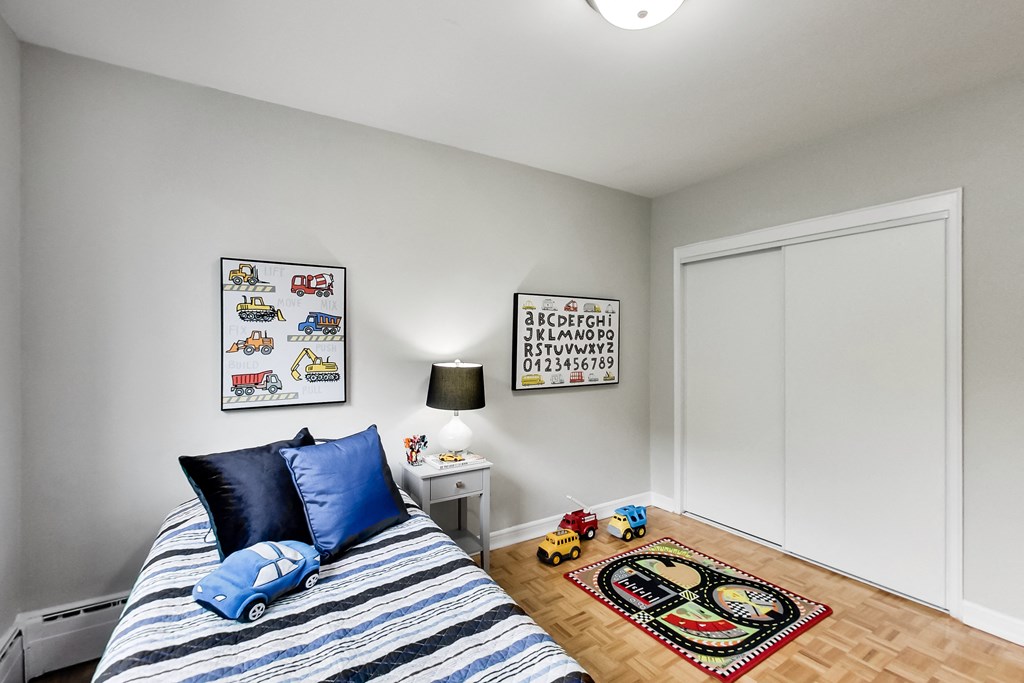 a bedroom with a bed with blue pillows and a toy car