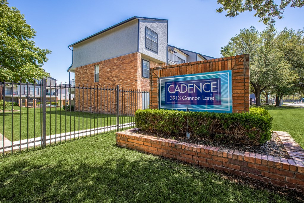 A sign for Cadence at 391 Gannon Lane sits in front of a brick building.