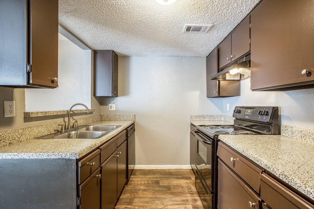 A kitchen with brown cabinets and a granite countertop.