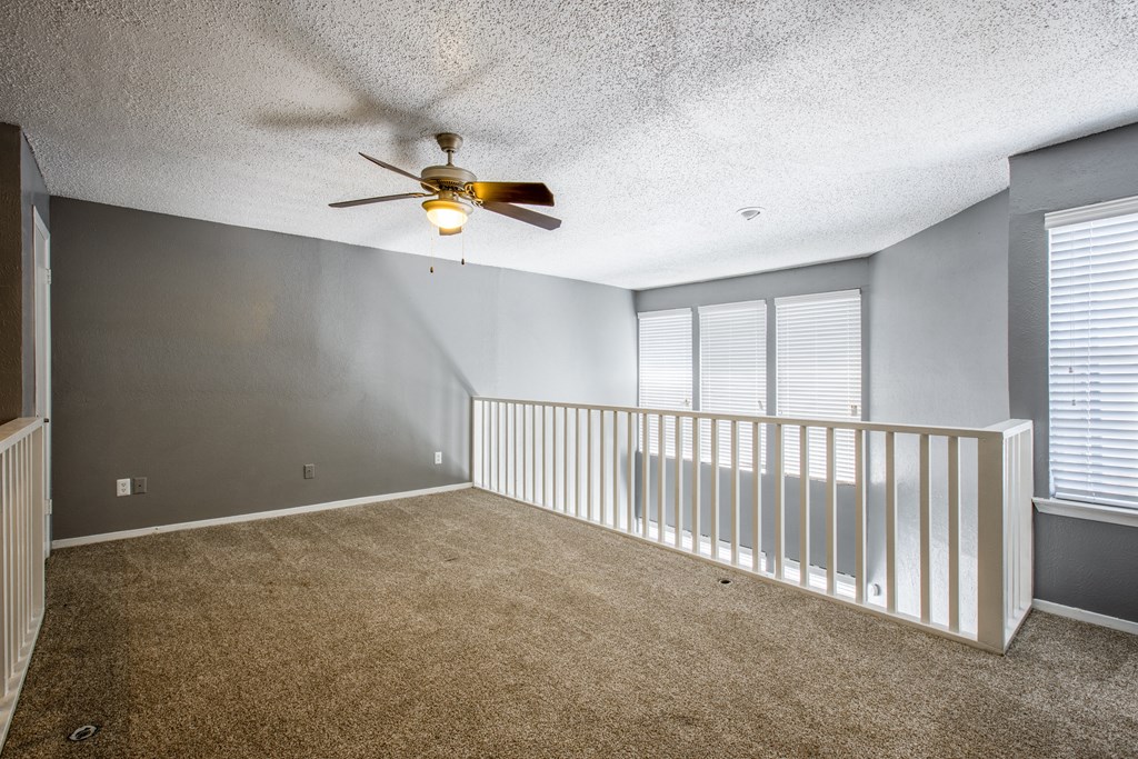 A room with a ceiling fan and carpeted floor.