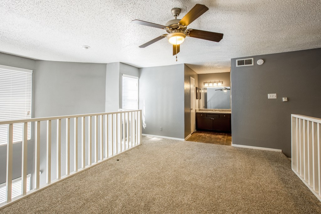 A room with a ceiling fan and carpeted floor.