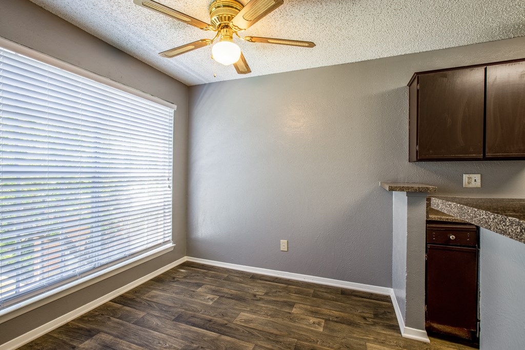 A room with a ceiling fan and a window with blinds.