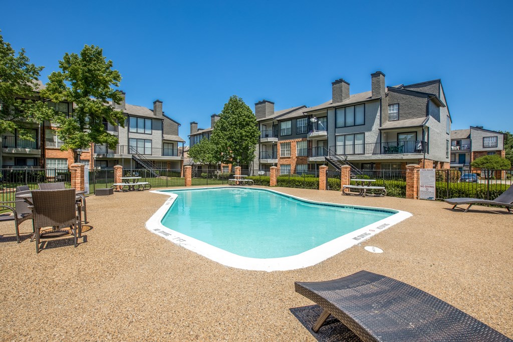 A swimming pool surrounded by a fence and chairs.