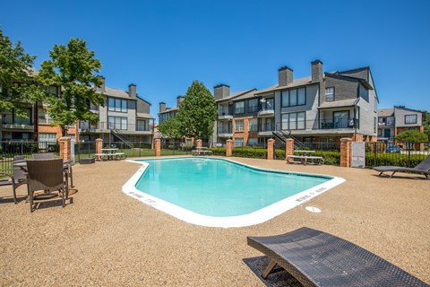 A swimming pool surrounded by a fence and chairs.