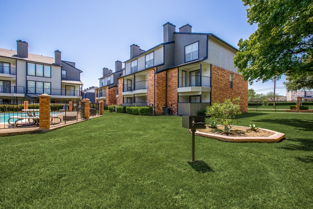 A grassy area in front of a building with a mailbox.