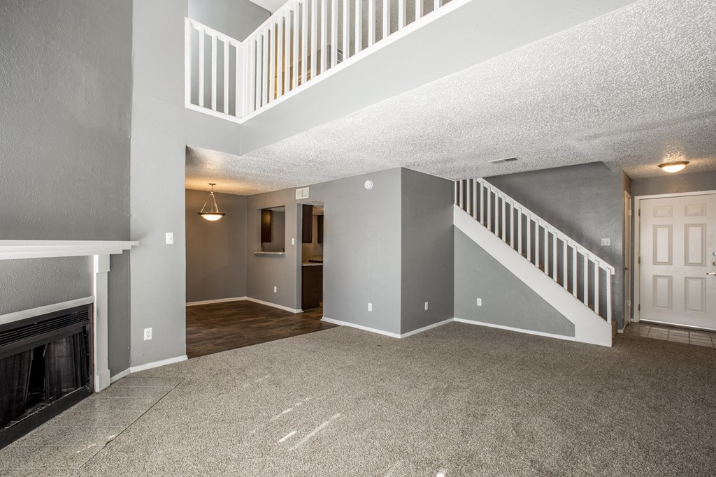 A spacious living room with a fireplace and a staircase.