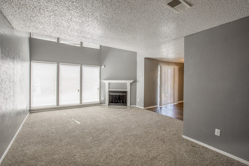 A sparsely furnished living room with a fireplace and sliding glass doors.