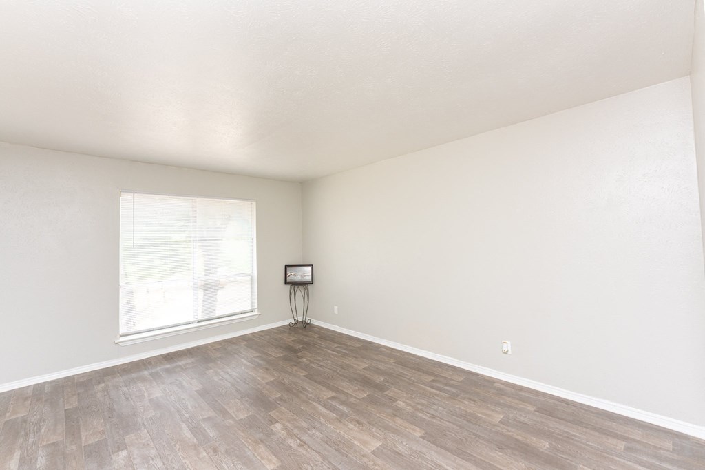 an empty living room with wood flooring and a window