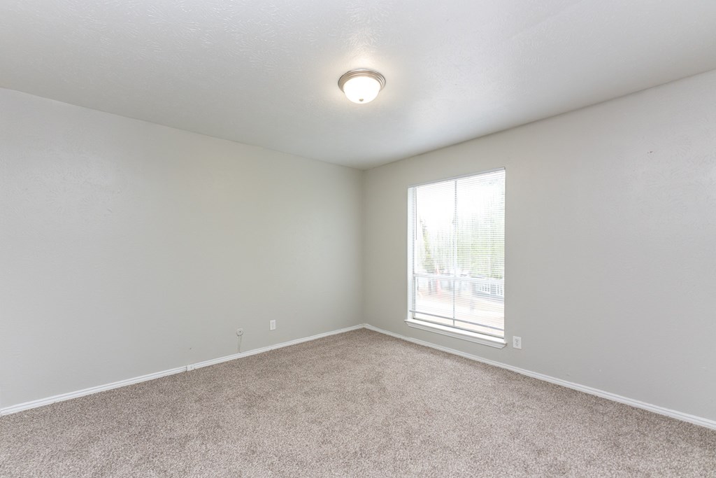 an empty living room with a window and carpet