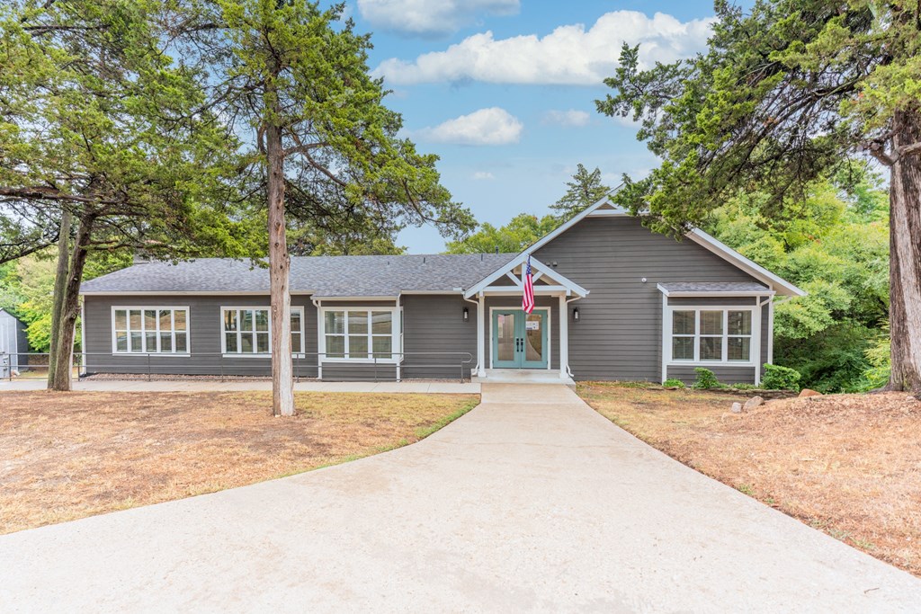 the front of a house with a driveway and trees