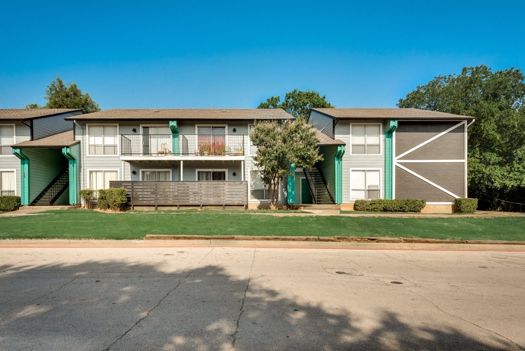 an exterior view of an apartment building on the side of a street