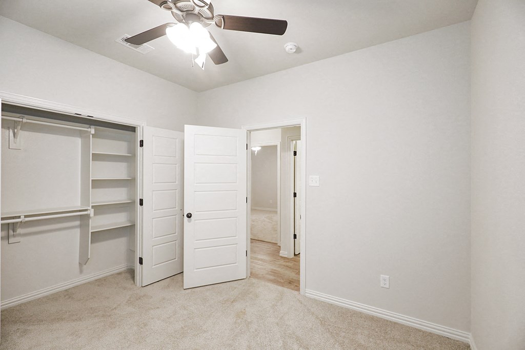 an empty bedroom with a closet and a ceiling fan