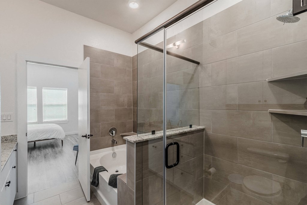 a bathroom with a shower and a tub and a bed