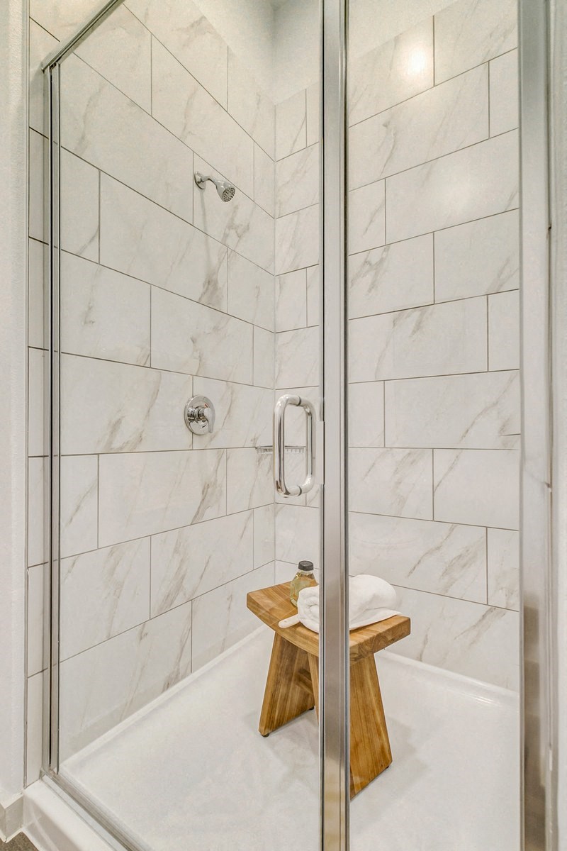 a bathroom with a shower and a stool in it