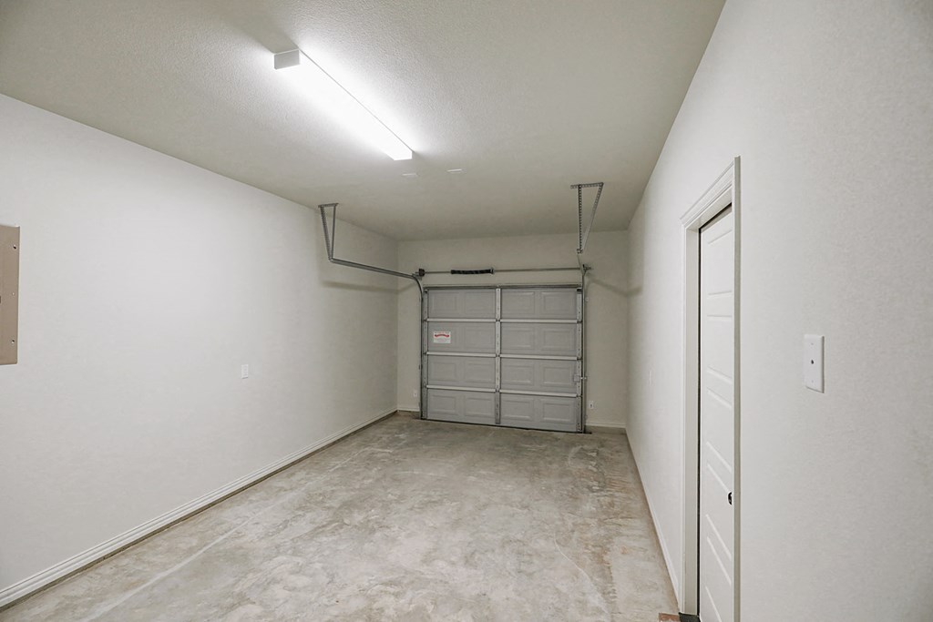 an empty room with a garage door and a white wall