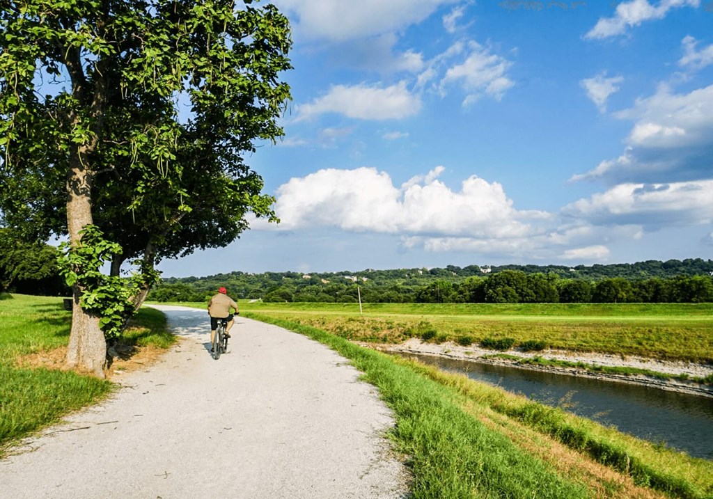 a man riding a bike down a dirt path next to a river