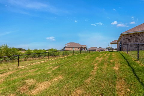 a fenced in backyard with houses in the background