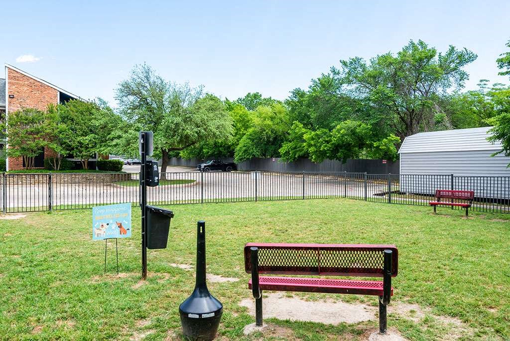 a bench in a park next to a fence