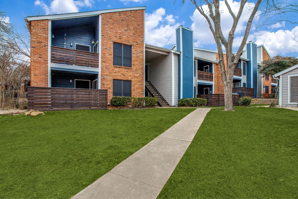a sidewalk in front of a building with grass