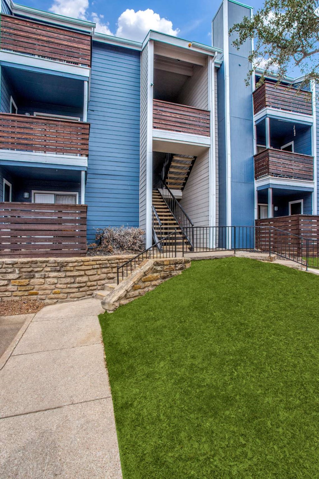 front view of an apartment building with a lawn and sidewalk