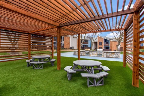 a picnic area with benches and tables under a wooden pergola