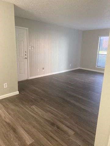 an empty living room with a wooden floor