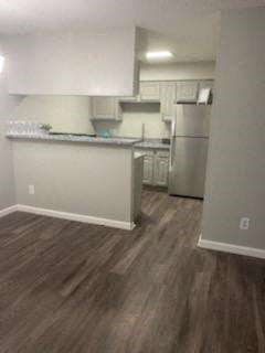 an empty living room and kitchen with a wood floor