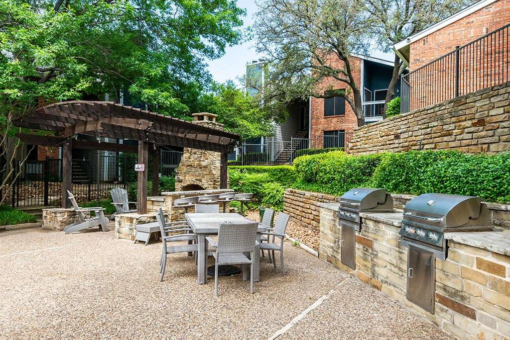 a patio with tables and chairs and a barbecue grill