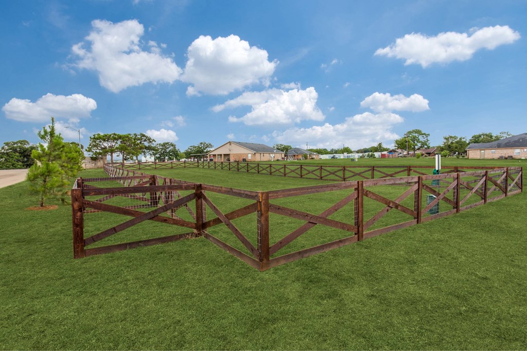 a pasture with a wooden fence and a farm in the background