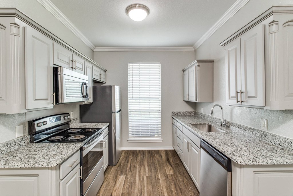 a kitchen with white cabinets and granite counter tops