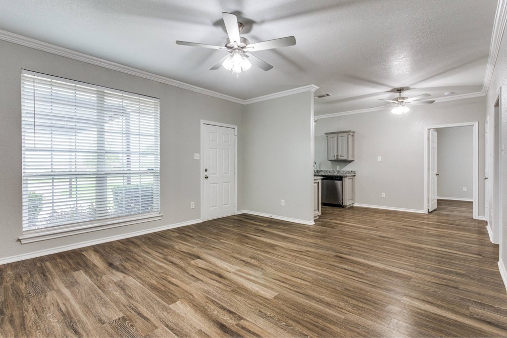 an empty living room with a large window and a ceiling fan