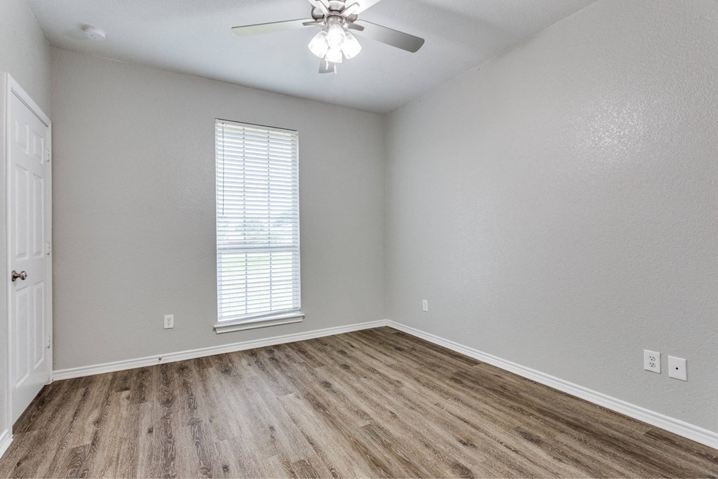an empty living room with wood flooring and a ceiling fan