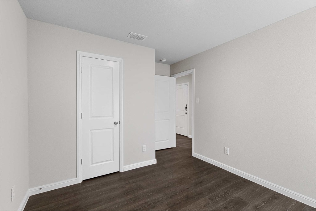 an empty bedroom with white walls and wood floors