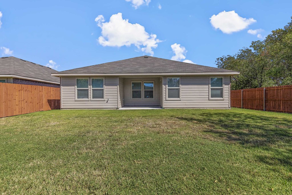 a beige house with a yard and a wooden fence