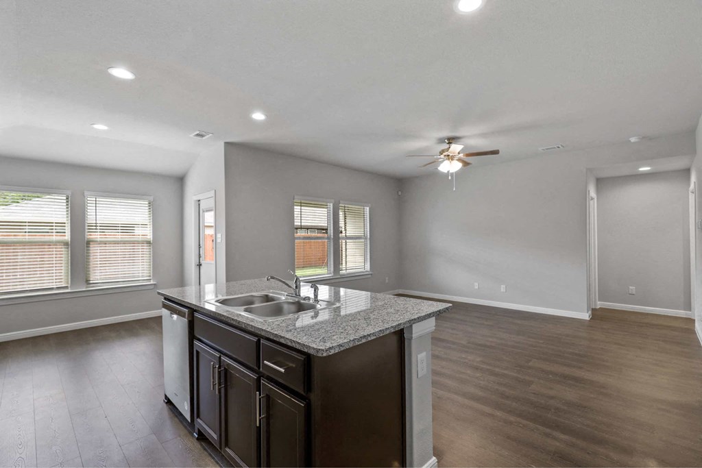 an empty kitchen with a sink and a ceiling fan