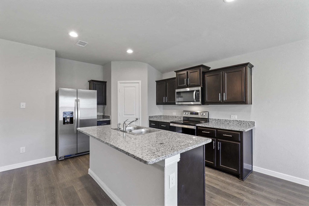 a kitchen with granite counter tops and a stainless steel refrigerator