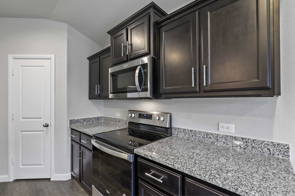 a kitchen with granite counter tops and black cabinets