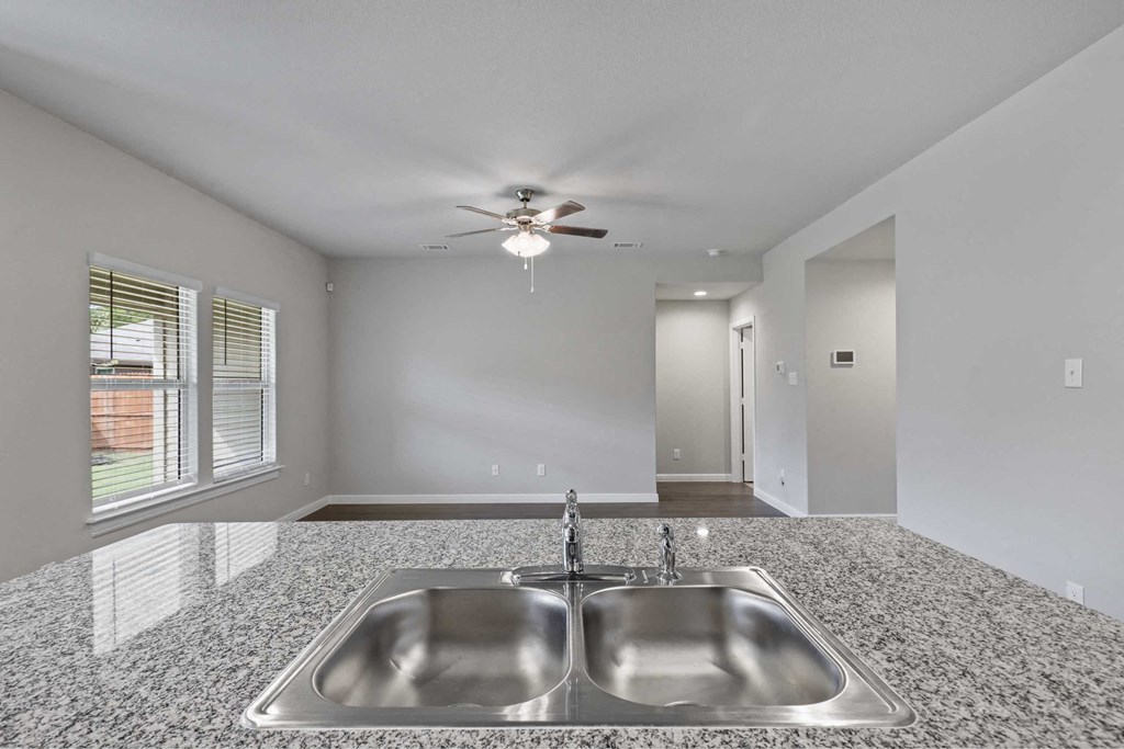 an empty kitchen with a sink and a ceiling fan