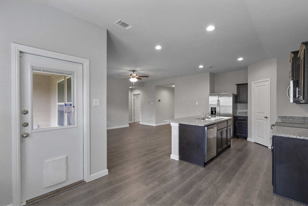 a renovated kitchen and living room with a ceiling fan