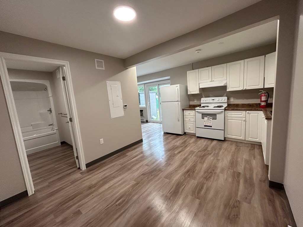 A kitchen with white cabinets and a wooden floor.