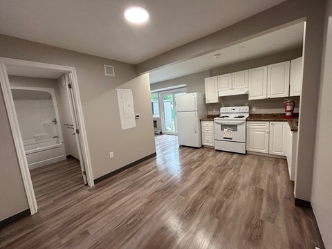 A kitchen with white cabinets and a wooden floor.