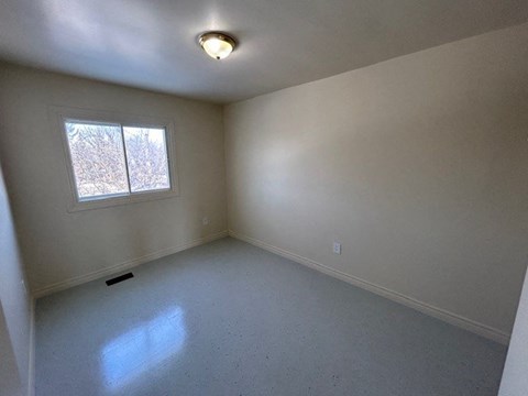 an empty room with a window and a ceiling light