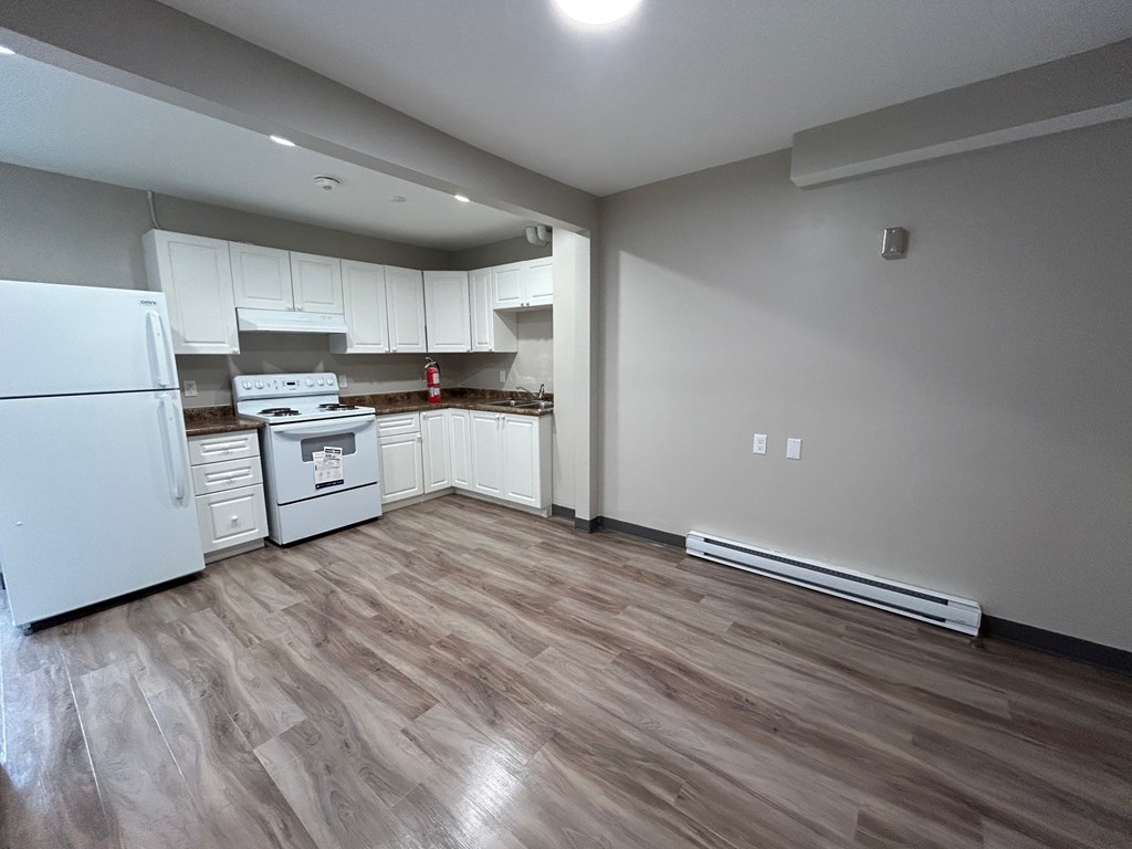 A kitchen with white appliances and wood flooring.