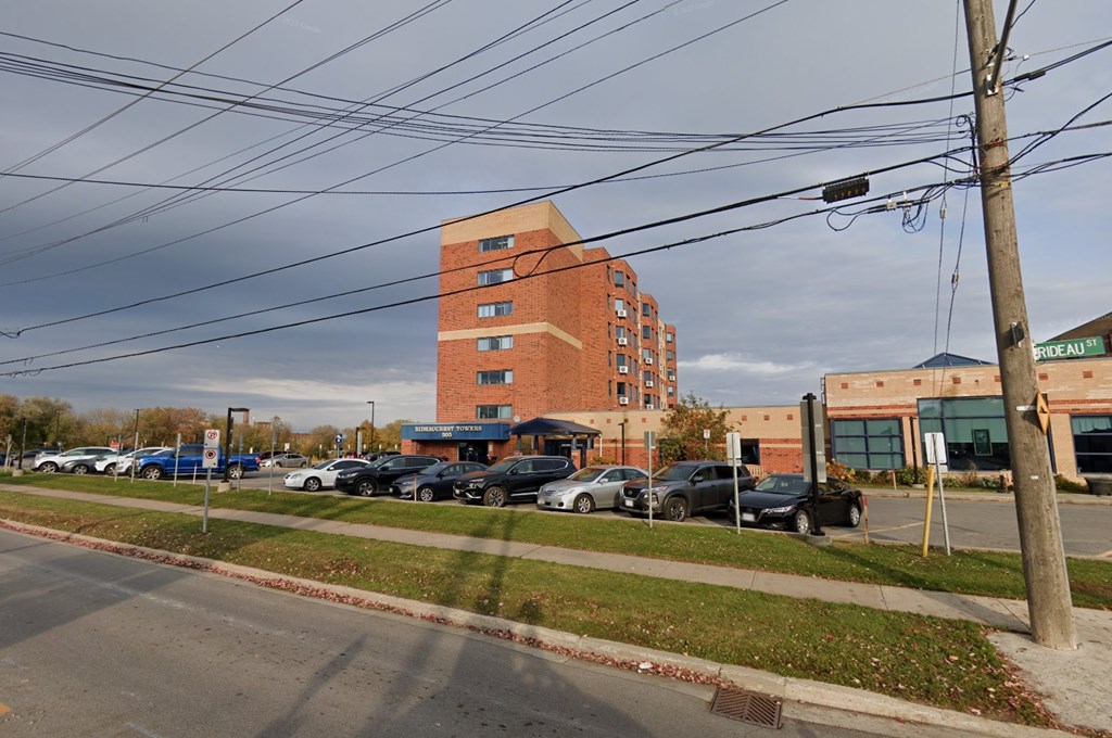 A parking lot with cars and a tall brick building in the background.